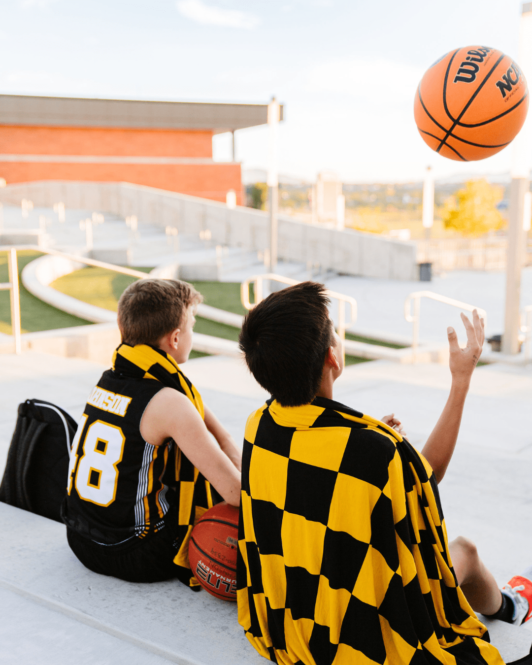 2 basketball players staying cozy in between chilly practice and game times. 